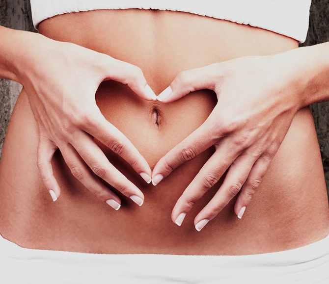 A woman holding her belly making a heart shape